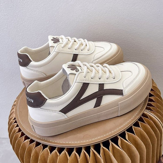Weiße Sneaker mit braunen Details auf modernem, gefaltetem Kartonhocker. Modische Turnschuhe, Lederoptik, trendiges Design, bequeme Sohle.