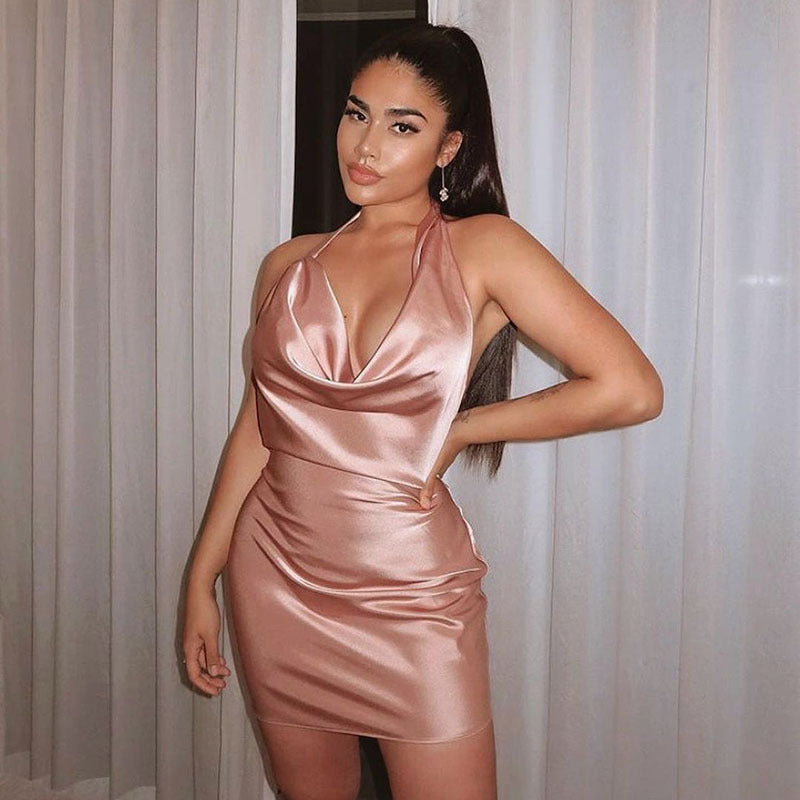 Frau in elegantem, roségoldenem Satin-Kleid vor weißen Vorhängen, Abendmode, glamouröser Look, modisches Outfit, stilvolle Kleidung.