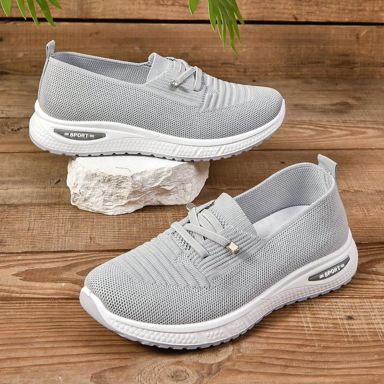 Graue Sportschuhe aus atmungsaktivem Mesh-Gewebe auf Holzboden, ideal für Laufen und Fitness. Leichte, rutschfeste Sohle für optimalen Komfort.