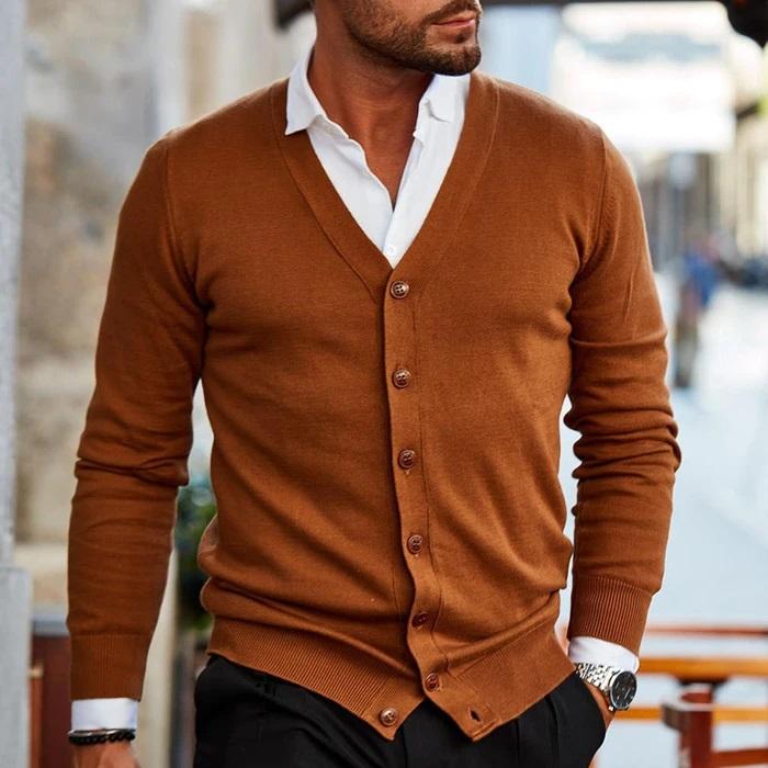 Mann in braunem Cardigan und weißem Hemd, stilvoll gekleidet, geht auf einer städtischen Straße. Elegante Herrenmode, Herbstoutfit, urbane Mode.