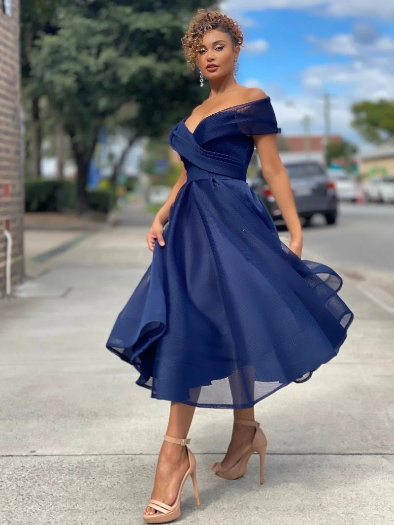 Elegantes, blaues Cocktailkleid mit schulterfreiem Design, getragen von einer Frau auf einer städtischen Straße. Perfekt für Abendveranstaltungen und Partys.