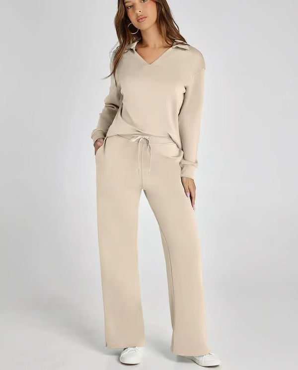 Frau in beigem Lounge-Set mit V-Ausschnitt und Kordelzughose, lässig und bequem, modisches Freizeitoutfit, weiße Sneaker, neutraler Hintergrund.