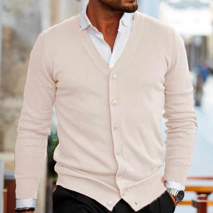 Eleganter Mann in beigem Cardigan und weißem Hemd, modisch gekleidet, urbaner Hintergrund. Herrenmode, stilvoller Look, Freizeitkleidung.