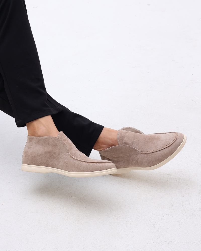 Beige Wildleder-Slipper für Damen, getragen mit schwarzer Hose. Bequeme, stilvolle Schuhe für Freizeit und Büro. Ideal für modische Outfits.