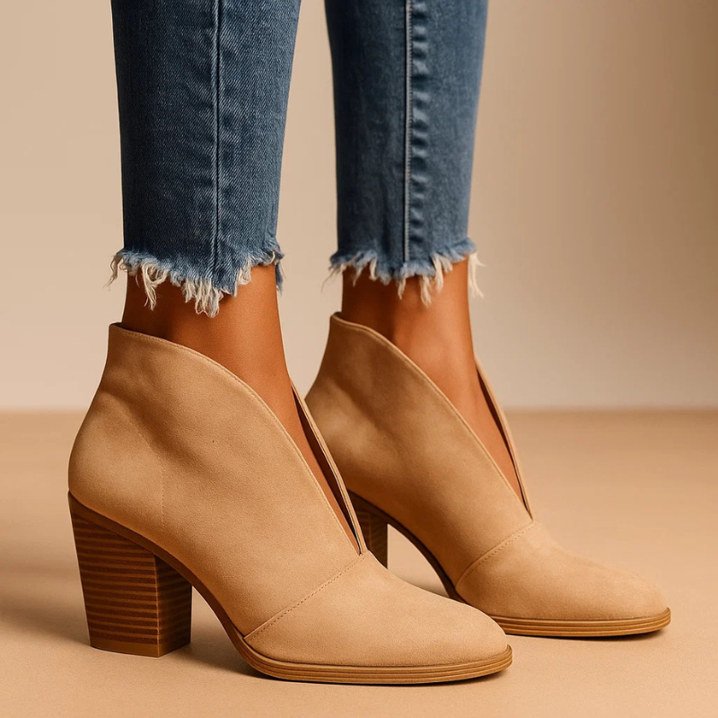 Beige Damen-Stiefeletten mit Blockabsatz, kombiniert mit ausgefransten blauen Jeans. Modische Herbstschuhe für Frauen, stilvoll und elegant.
