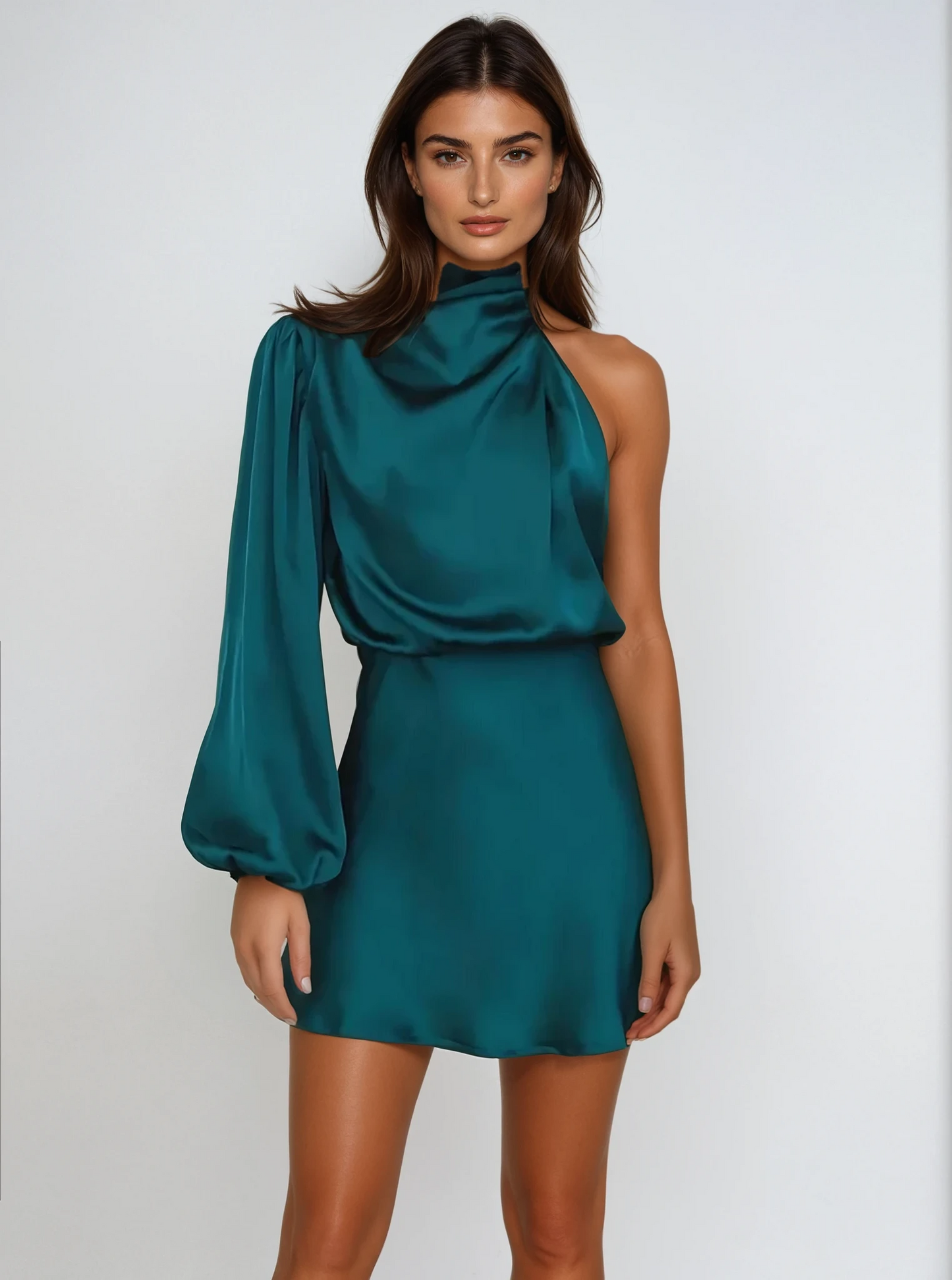 Frau in elegantem, einärmligem, smaragdgrünem Satin-Kleid vor weißem Hintergrund. Modetrend, Abendmode, stilvolles Design.