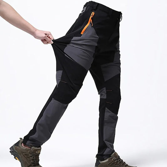 Schwarze und graue Outdoor-Hose mit elastischem Bund und orangefarbenem Reißverschluss, getragen von Person, zeigt Flexibilität und Komfort.
