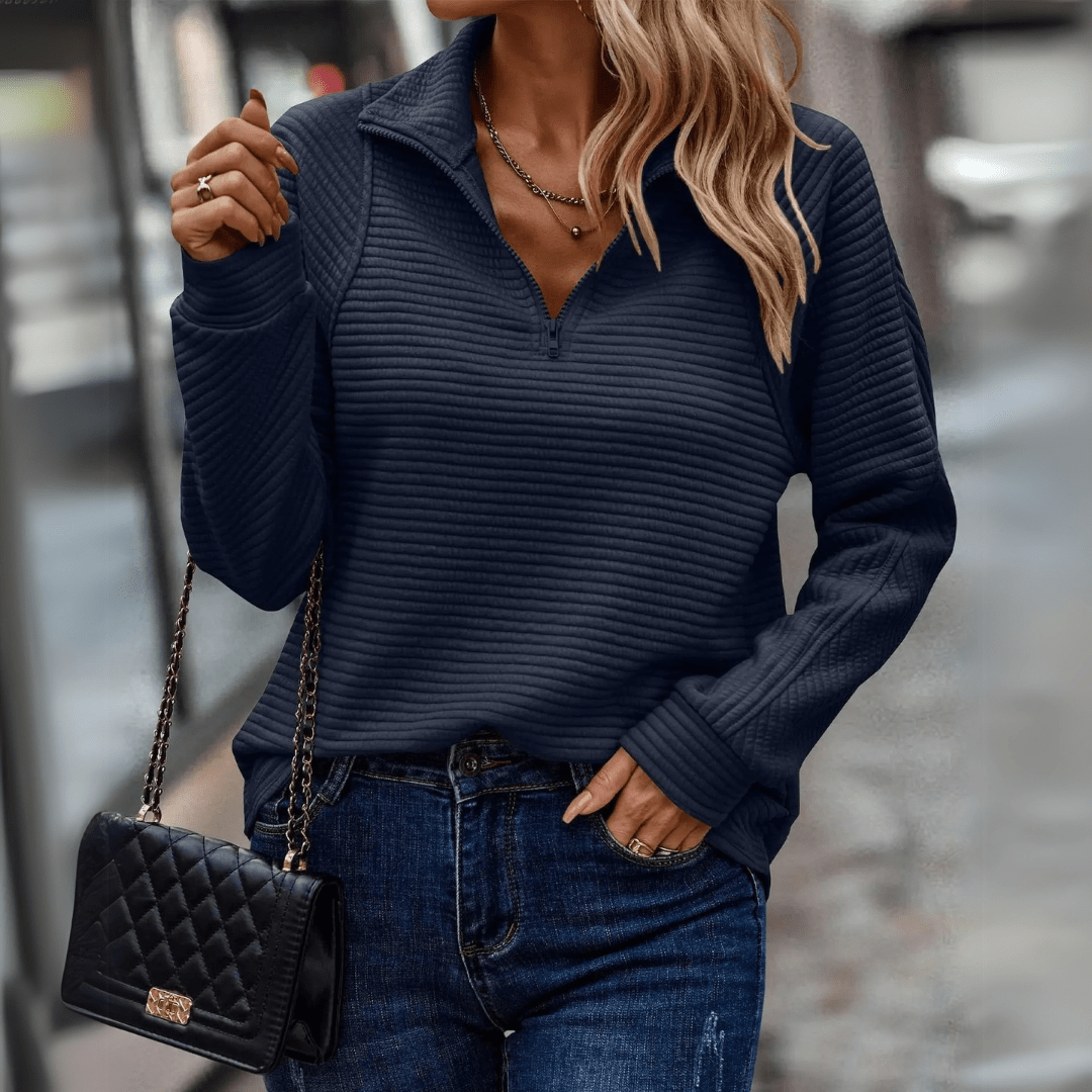 Frau in dunkelblauem Pullover und Jeans, trägt schwarze gesteppte Handtasche. Modetrend Herbst, lässiger Streetstyle, elegante Damenmode.