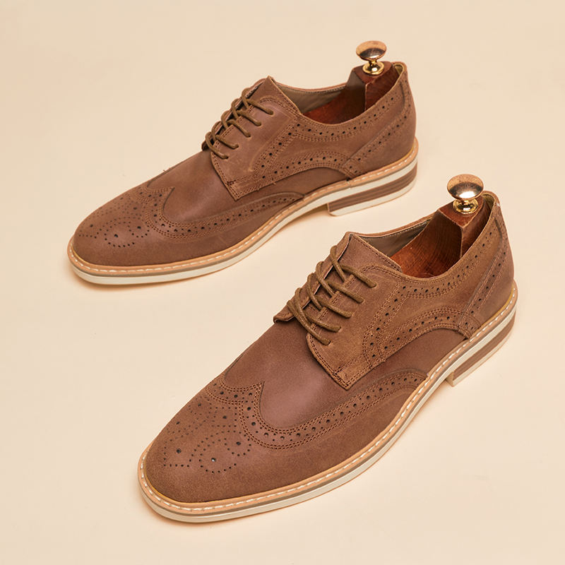 Braune Herren-Brogues aus Leder mit Lochmuster und Holz-Schuhspanner auf beigem Hintergrund. Elegante Herrenschuhe, klassisches Design.