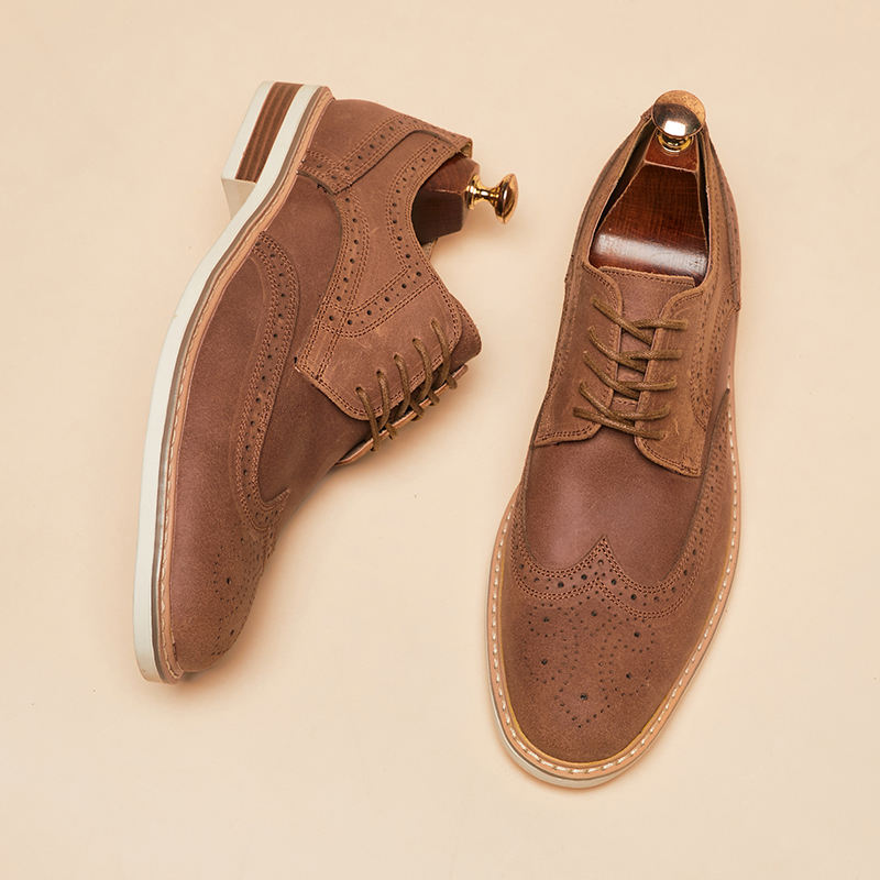 Braune Herren-Brogues aus Leder mit Lochmuster, Schnürung und Holzschuhspanner auf beigem Hintergrund. Elegante Herrenschuhe, klassisches Design.