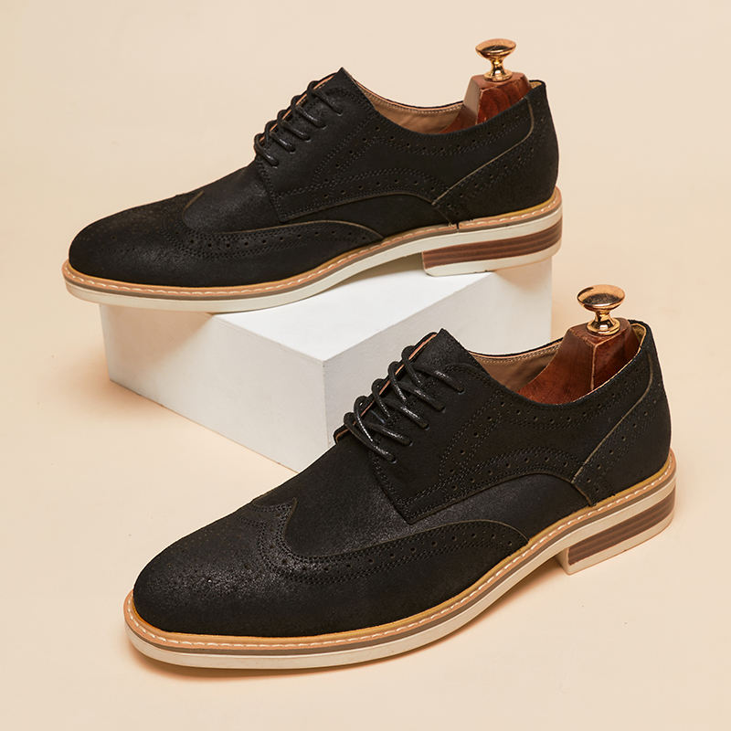 Schwarze Herren-Brogues aus Leder mit Lochmuster, auf weißem Podest präsentiert. Elegante Schnürschuhe, ideal für Business und formelle Anlässe.