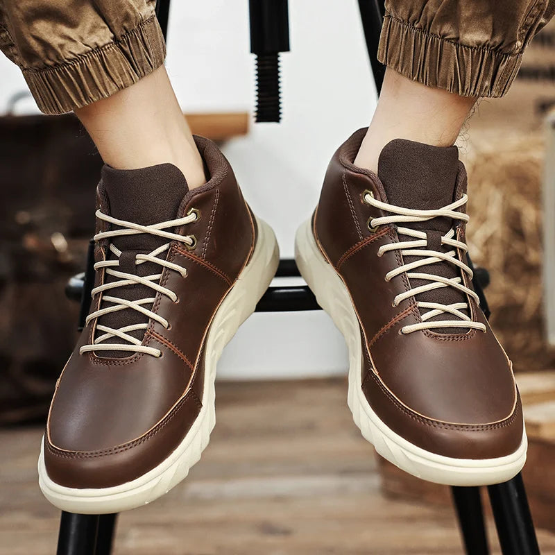 Braune Herren-Sneaker aus Leder mit beiger Sohle und Schnürsenkeln, getragen von einer Person in hochgekrempelten Hosen.