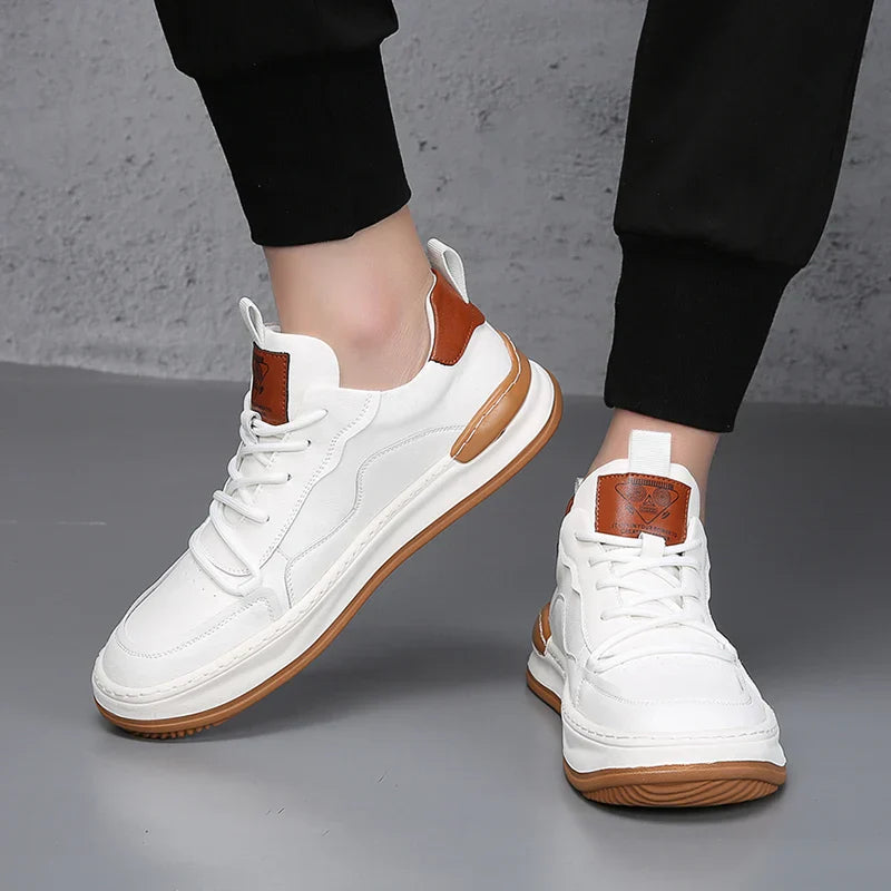 Weiße Sneaker mit braunen Akzenten, getragen von einer Person auf grauem Boden. Modische Turnschuhe, bequeme Freizeitschuhe, trendige Sportschuhe.
