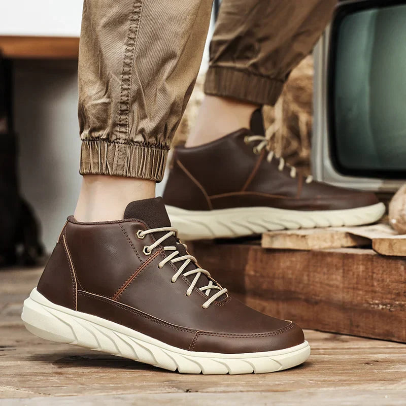 Braune Herren-Sneaker aus Leder mit beiger Sohle, getragen von Person in hochgekrempelten Hosen. Modische, bequeme Freizeitschuhe für den Alltag.
