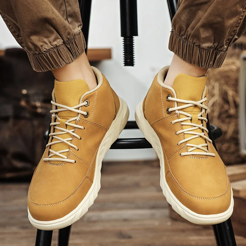 Braune Herren-Wanderschuhe aus Leder mit heller Sohle, getragen von einer Person auf einem Hocker. Outdoor-Schuhe, robust, modisch.