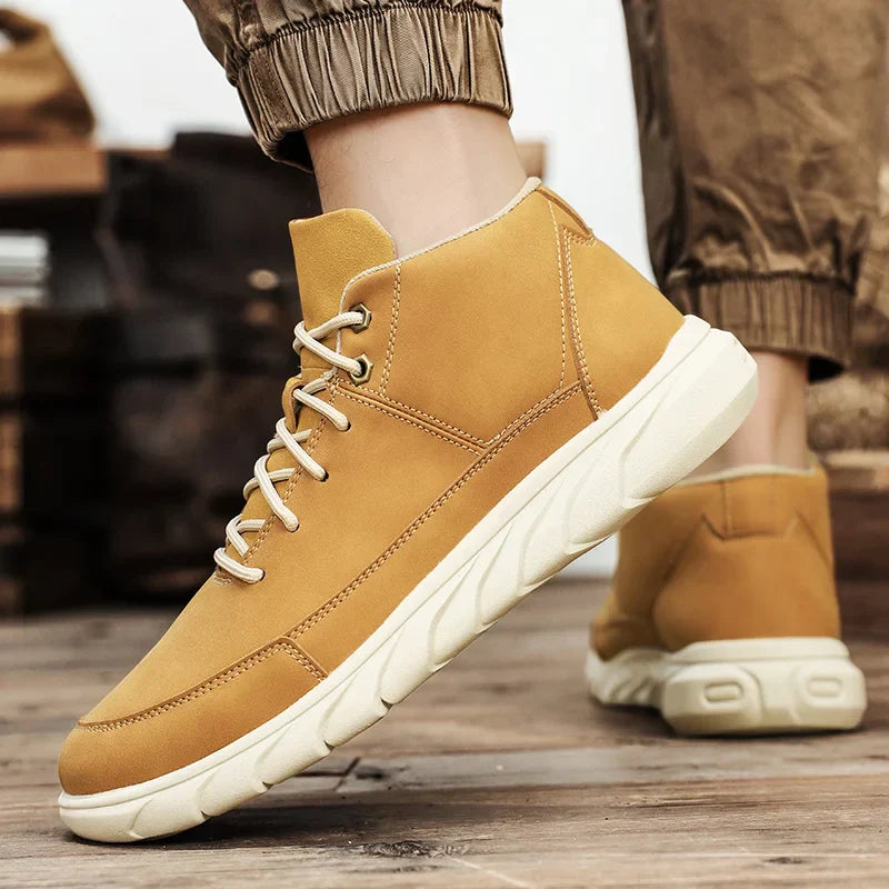 Beige Herren-Sneaker aus Leder mit weißer Sohle, getragen auf Holzboden. Modische Freizeitschuhe, ideal für Herbstmode und Outdoor-Aktivitäten.