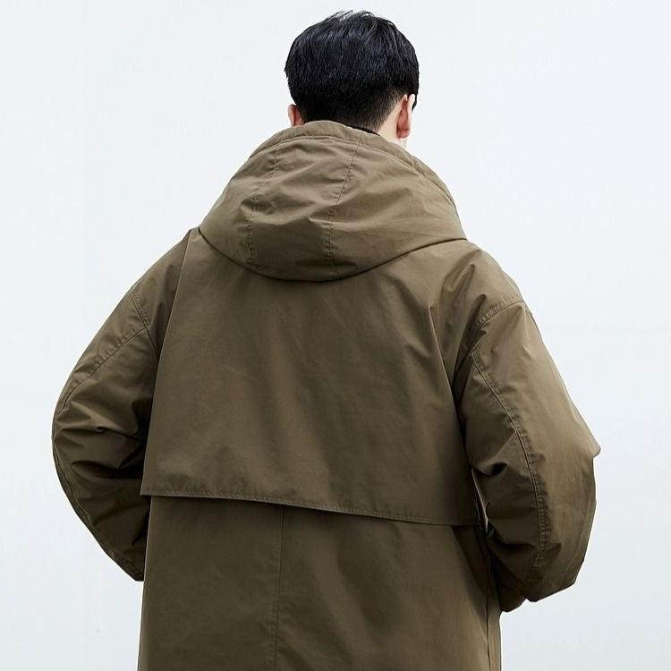 Rückansicht eines Mannes in olivgrünem Parka mit Kapuze. Modischer Herrenmantel, Outdoor-Bekleidung, Herbstmode, wetterfest.