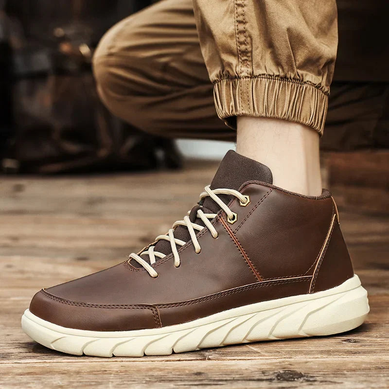Brauner Herren-Sneaker aus Leder mit weißer Sohle, getragen von Person in beigefarbener Hose. Modischer Freizeitschuh für Herbst und Winter.