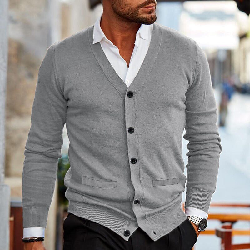 Eleganter Mann in grauem Cardigan und weißem Hemd, modischer Look, urbane Umgebung, stilvolle Herrenmode, zeitloser Stil, moderne Eleganz.