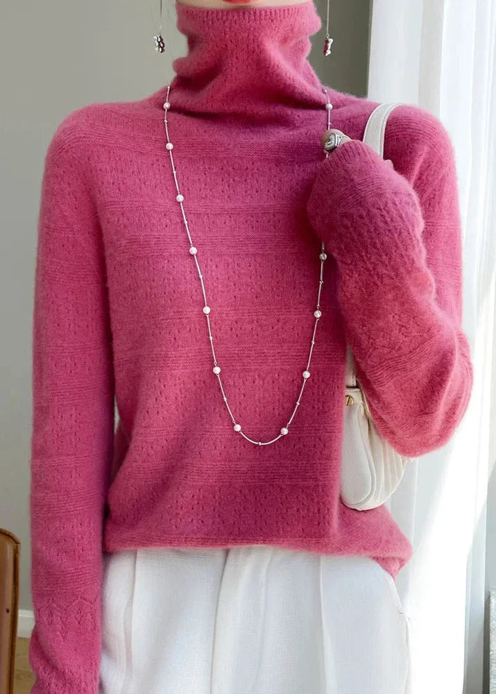 Frau in pinkem Rollkragenpullover mit Perlenkette und weißer Tasche, modisches Outfit, eleganter Look, Herbstmode, Damenbekleidung.
