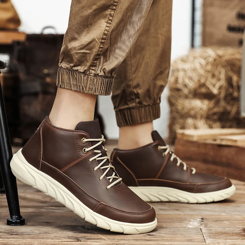 Braune Herren-Sneaker aus Leder mit weißen Sohlen, getragen zu hochgekrempelten, beige Hosen. Modische, bequeme Freizeitschuhe für den Herbst.
