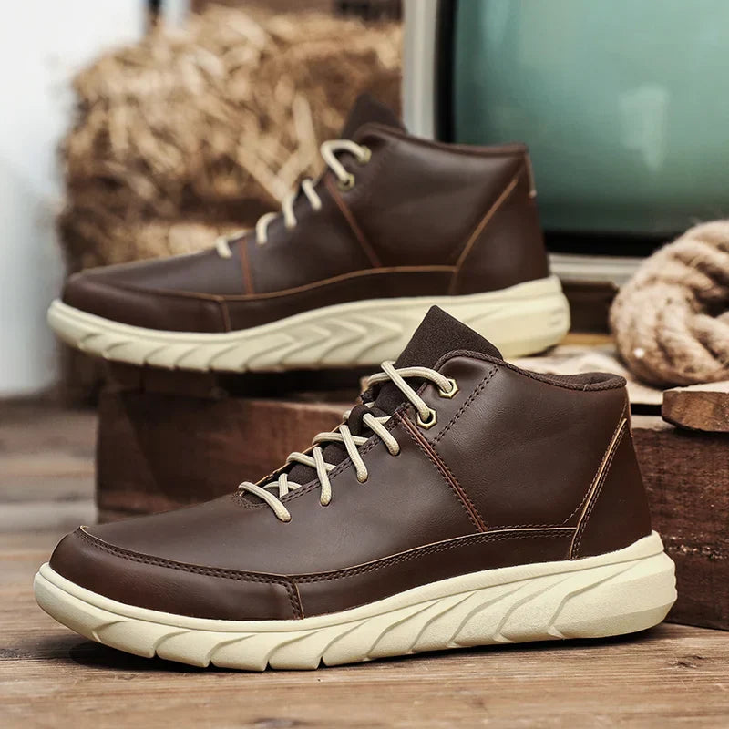 Braune Herren-Wanderschuhe mit weißer Sohle, aus Leder, auf Holzboden vor rustikalem Hintergrund. Outdoor-Schuhe, bequem, stilvoll.