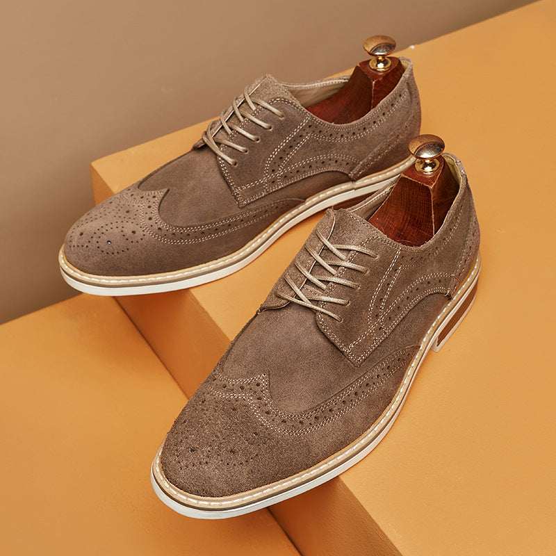 Braune Herren-Brogues aus Wildleder mit Lochmuster und Holz-Schuhspannern auf beigem Hintergrund. Elegante Lederschuhe, klassische Mode.