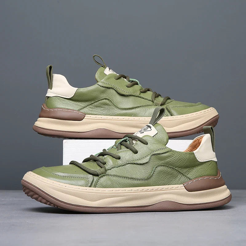 Grüne Ledersneaker mit beiger Sohle, modernem Design und Schnürung, auf grauem Hintergrund. Trendige Herrenschuhe, ideal für Freizeitmode.