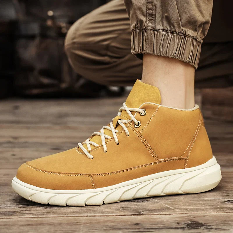 Beige Herren-Sneaker aus Leder mit weißer Sohle, getragen auf Holzboden. Modische, bequeme Schuhe für Freizeit und Outdoor-Aktivitäten.