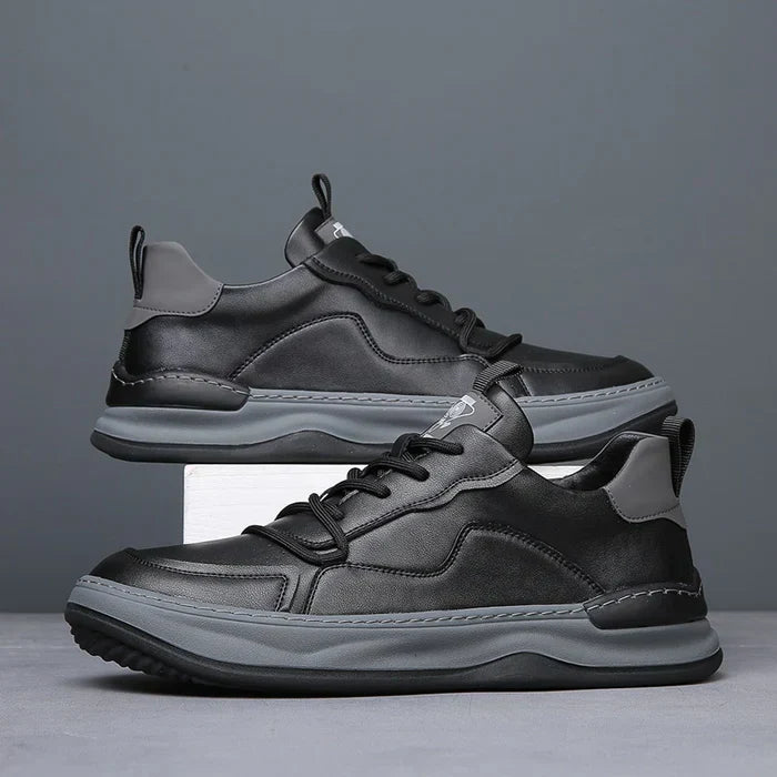 Schwarze Herren-Sneaker aus Leder mit grauen Akzenten, seitlich aufgestellt. Modische Freizeitschuhe, ideal für urbanen Stil und Komfort.