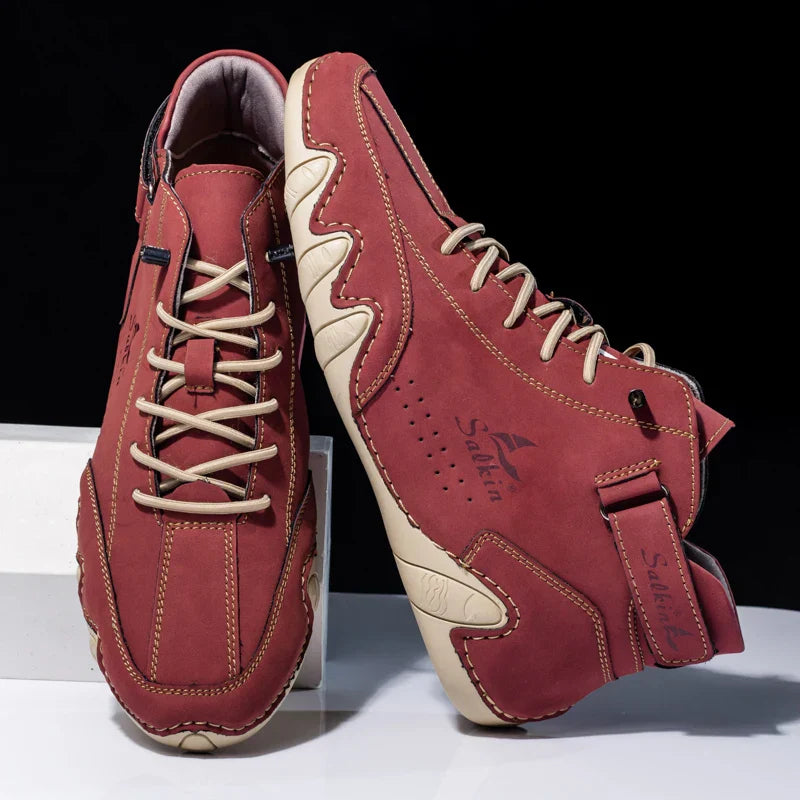 Rote Lederschuhe mit beiger Sohle, sportliches Design, seitliche Ziernähte, Markenlogo sichtbar, ideal für Freizeit und Outdoor-Aktivitäten.