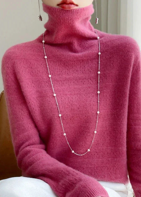Frau in rosa Rollkragenpullover mit langer Perlenkette, elegantes Outfit, modischer Look, stilvolle Damenbekleidung, Herbstmode.