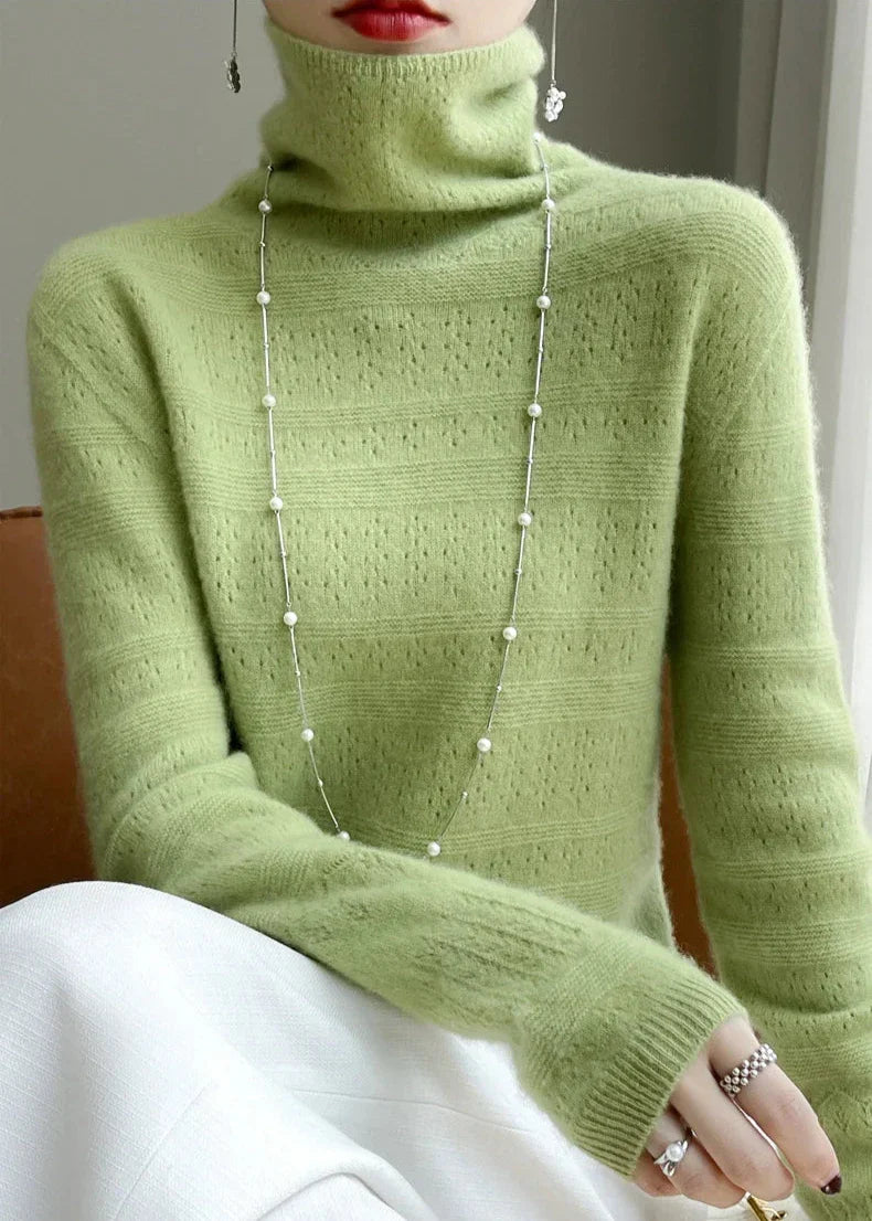 Frau in grünem Rollkragenpullover mit Perlenkette, elegantes Outfit, modischer Look, stilvolle Winterkleidung, Damenmode, Strickpullover.