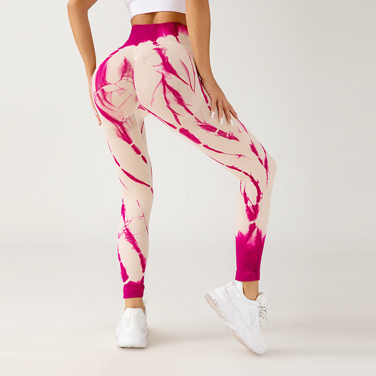 Frau in pink-weiß gemusterten Leggings, Rückansicht, sportlich, modisch, Fitnessbekleidung, weiße Turnschuhe, athletischer Stil, neutraler Hintergrund.