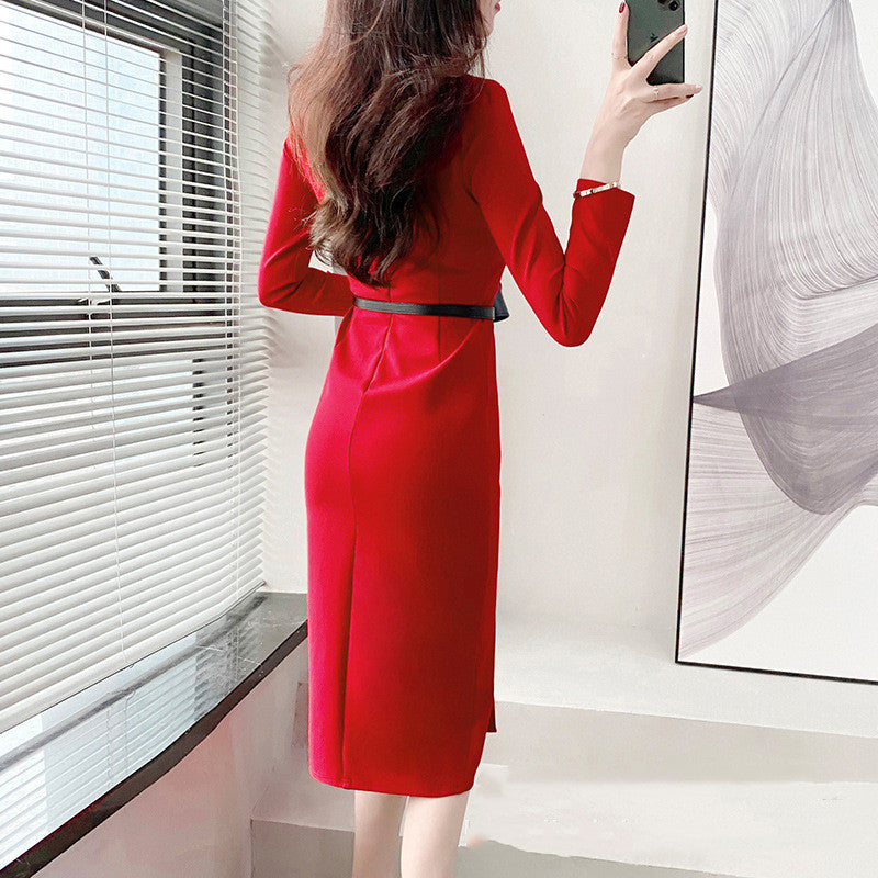 Frau in rotem Kleid steht vor Fenster, hält Smartphone. Elegantes, figurbetontes Design, modernes Interieur. Mode, Damenbekleidung, Stil.