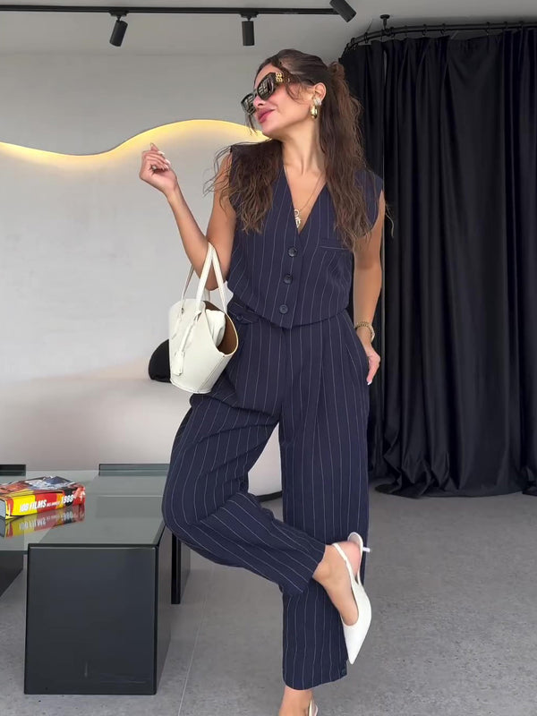 Frau in gestreiftem, dunkelblauem Anzug posiert stilvoll mit weißer Handtasche und Sonnenbrille. Elegante Mode, Business-Look, moderne Frau.