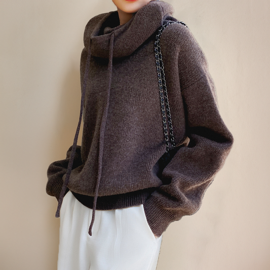 Dunkelbrauner Strickpullover mit Rollkragen und Kordeln, kombiniert mit weißer Hose. Modetrend Herbst/Winter, gemütlicher Look, Damenmode.