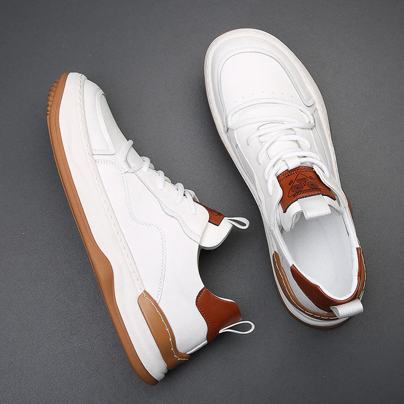 Weiße Sneaker mit braunen Akzenten und Gummisohle auf grauem Hintergrund. Modische Herrenschuhe, ideal für Freizeit und Sport.