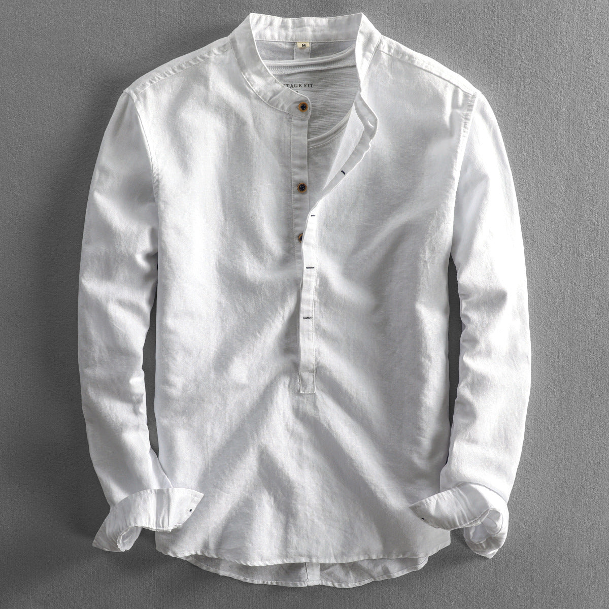 Weiße Leinenhemd für Herren mit Stehkragen und Knopfleiste, langärmlig, auf grauem Hintergrund. Elegante Herrenmode, ideal für Sommer.