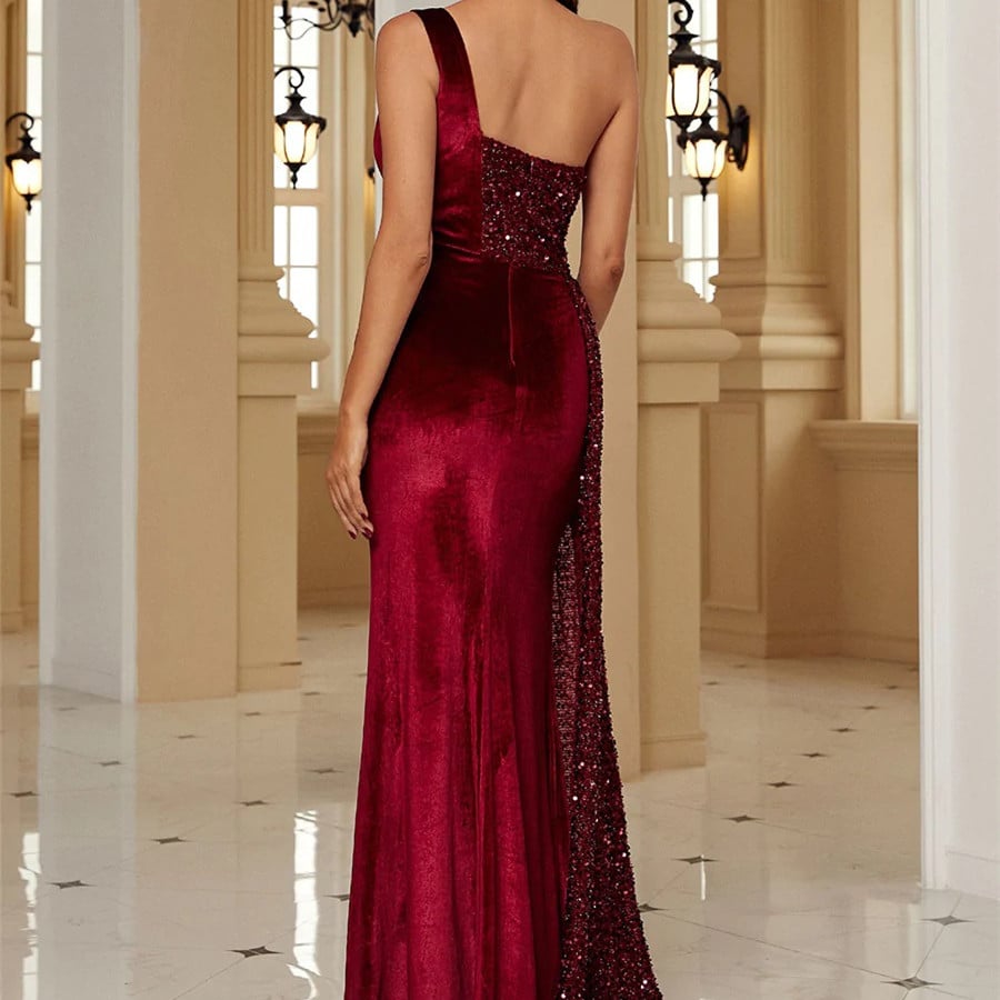 Rückansicht einer Frau in einem eleganten, roten Abendkleid mit Pailletten, stehend in einem luxuriösen, hellen Raum mit Kronleuchtern.