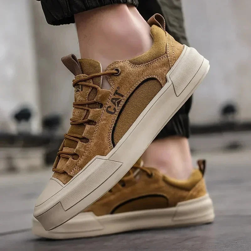 Braune CAT Sneaker aus Wildleder, seitlich fotografiert, mit weißer Sohle und Schnürsenkeln. Modische Herrenschuhe, ideal für Freizeit und Outdoor.
