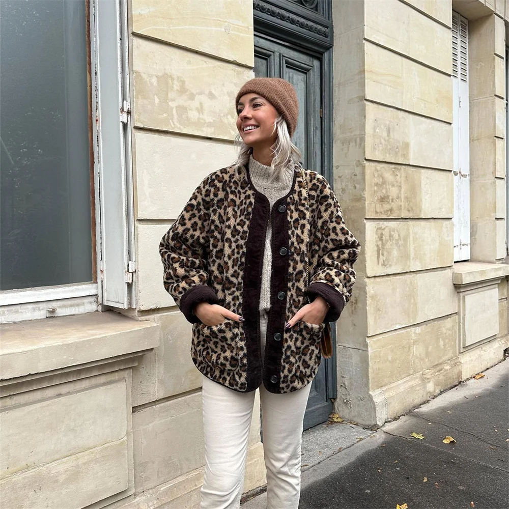 Frau in Leopardenmuster-Jacke, beiger Mütze und weißer Hose vor einem Gebäude. Herbstmode, Streetstyle, trendige Damenbekleidung.