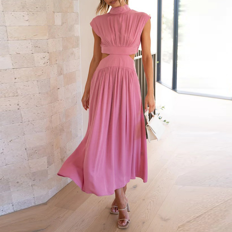Elegantes rosa Maxikleid, ärmellos, mit fließendem Rock und Taillengürtel, getragen von Frau in modernem Innenraum, modische Sommermode.