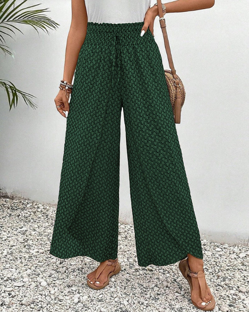 Grüne Damenhose mit weitem Bein, gemustert, kombiniert mit braunen Sandalen und einer Umhängetasche, ideal für Sommermode und Freizeitoutfits.