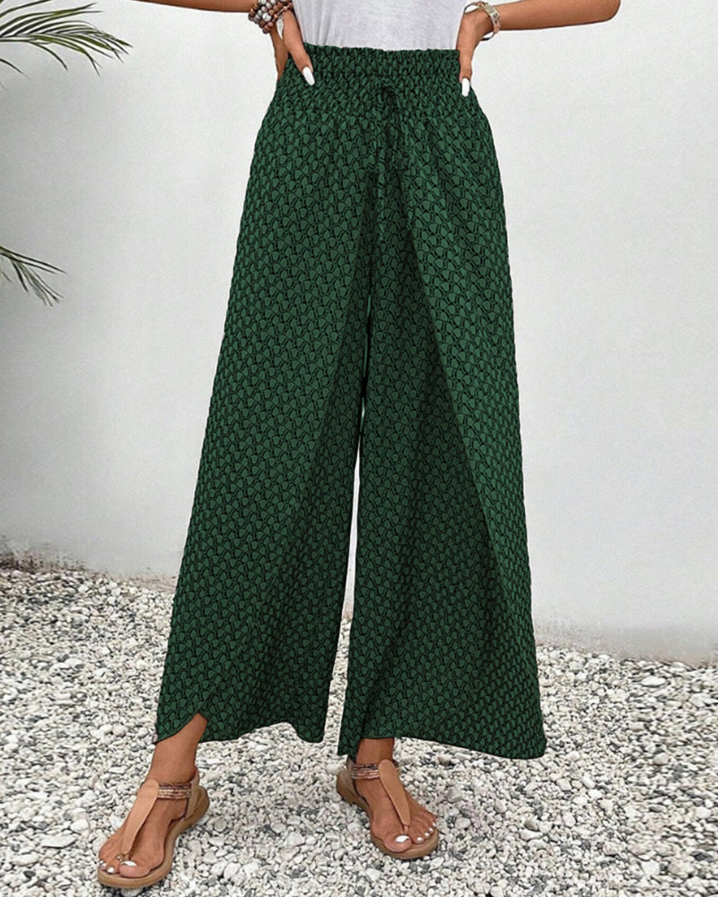 Frau trägt grüne, gemusterte Palazzo-Hose, kombiniert mit Sandalen. Sommermode, Damenbekleidung, lässiger Stil, trendige weite Hosen.