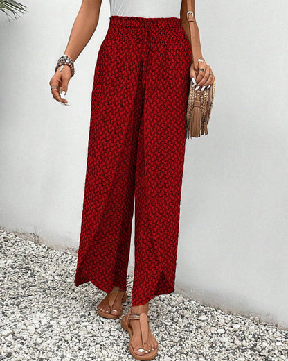 Frau in roter, gemusterter Hose und Sandalen, hält eine Fransenhandtasche. Sommermode, lässiger Stil, Damenbekleidung, modische Accessoires.