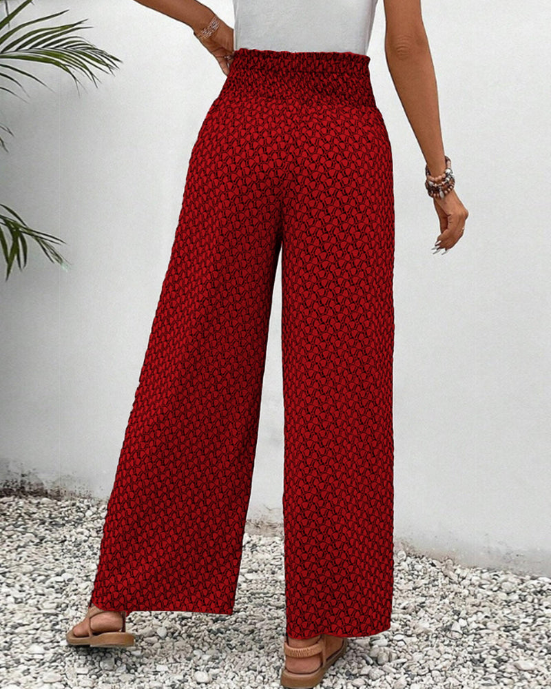 Frau in roter, gemusterter Schlaghose, steht auf Kiesweg. Sommermode, weite Hose, Freizeitlook. Ideal für lässige Anlässe und warme Tage.