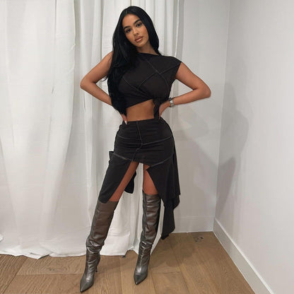 Frau in schwarzem, asymmetrischem Kleid und silbernen Stiefeln posiert vor weißem Vorhang. Mode, Abendkleid, trendiger Look.