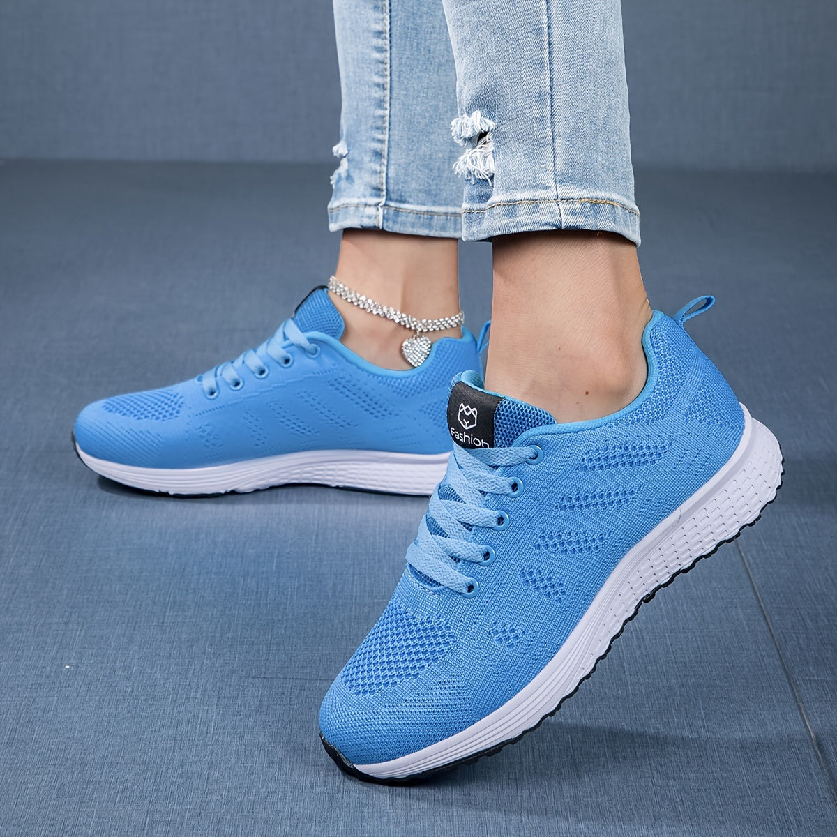 Blaue Damen-Sneaker mit weißer Sohle, getragen mit zerrissenen Jeans. Bequeme Sportschuhe, modisch, ideal für Freizeit und Sport.