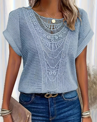 Frau trägt hellblauen, gehäkelten Pullover mit Spitzenmuster, kombiniert mit blauer Jeans. Modetrend, Damenmode, lässiger Look.